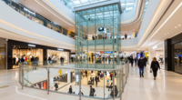 Makedonya'nın başkenti Skopje'deki büyük alışveriş merkezi, modern yapı ve alışveriş yapan insanlar