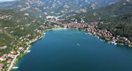 Ohrid Gölü'nün görselini, yeşil dağlar ve temiz mavi su ile çevrelenmiş şekilde gösteren foto-gerçekçi bir resim