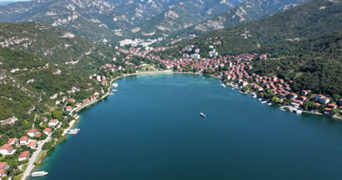 Ohrid Gölü'nün görselini, yeşil dağlar ve temiz mavi su ile çevrelenmiş şekilde gösteren foto-gerçekçi bir resim